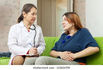 Woman Complaining  To Doctor About Abdominal Pain At Home