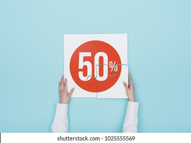 Woman completing a puzzle with a 50% off discount icon, she is putting the missing piece, shopping and discounts concept