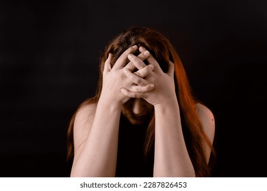 Woman with complexes put head down covering face with hands. Female portrait isolated on black. Upset girl, introvert. Feelings, life difficulties. Human emotions, facial expression concept.