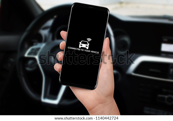 Woman\
connecting car with her smartphone and app using wifi. Wireless\
communication between smartphone and\
car.