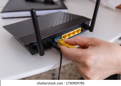 woman connects the internet cable to the router's socket. Fast and wireless internet concept - Shutterstock ID 1730909785