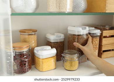 Woman with containers of different cereals and legumes in kitchen, closeup - Powered by Shutterstock