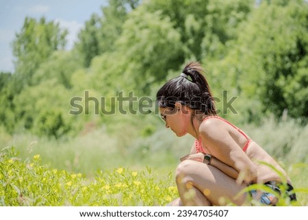 Woman contemplating flowers growing in the meadow.