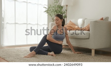 A woman in a contemplative yoga twist pose, expression serene, as engages in a mindful stretching routine that promotes flexibility and mental clarity