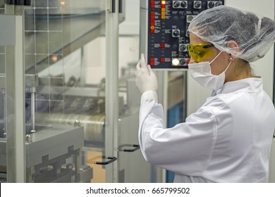 Woman At Control Panel Of Pharmaceutical Machine. A Female Technician Using The Control Panel Of Pill Packaging Machine. Pharmaceutical Manufacturing.
 Pharmaceutical Industry.