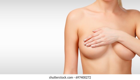 Woman controlling breast for cancer against a grey background with copyspace. Female healthcare concept