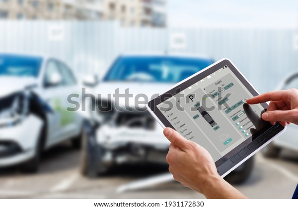 Woman controlling car with tablet application\
while standing near the vehicle outdoors, close-up view on the\
tablet with app interface