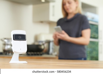 Woman Controlling Smart Security Camera Using App On Mobile Phone