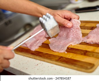 Woman cook beating turkey breast fillets with meat tenderizer - Powered by Shutterstock