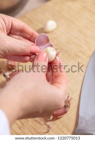 woman cook cleans garlic cloves, hands closeup