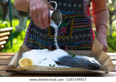 A woman cook a fish in a salt crust