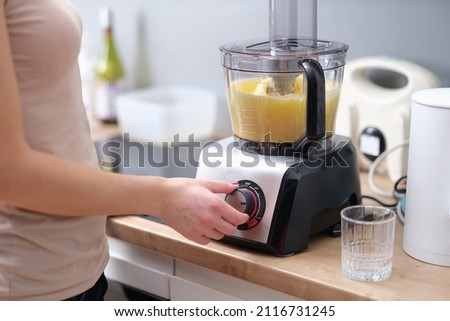 Woman cook turning on button of food processor for kneading dough closeup