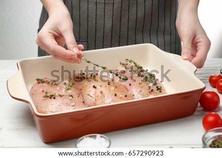 Woman cooking chicken parmesan with spices in kitchen