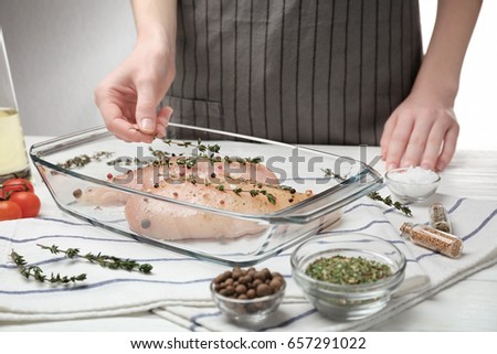 Woman cooking chicken parmesan with spices in kitchen