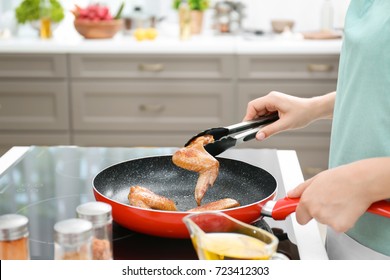 Woman Cooking Chicken Wings In Frying Pan On Stove