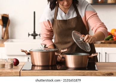 Woman cooking in copper pot at home - Shutterstock ID 2131651879