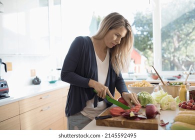 Woman cooking, cutting vegetables on cutting board at kitchen counter - Shutterstock ID 2145592495