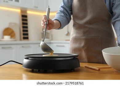 Woman cooking delicious crepe on electrical pancake maker in kitchen, closeup - Powered by Shutterstock