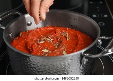 Woman Cooking Delicious Tomato Sauce In Pan On Stove, Closeup