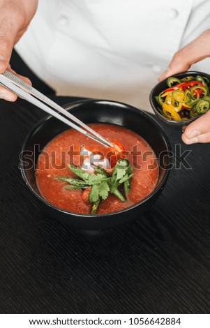 Woman cooking delicious tomato soup with parsley