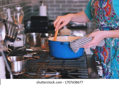 Woman Is Cooking Dinner In A Blue Cast Iron Pot, Dutch Oven, On A Stove