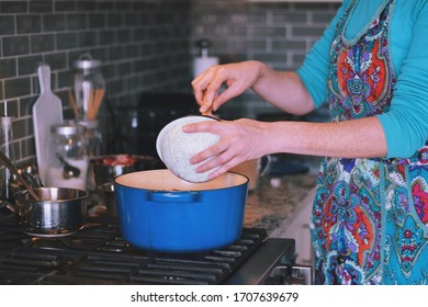 Woman Is Cooking Dinner In A Blue Cast Iron Pot, Dutch Oven, On A Stove