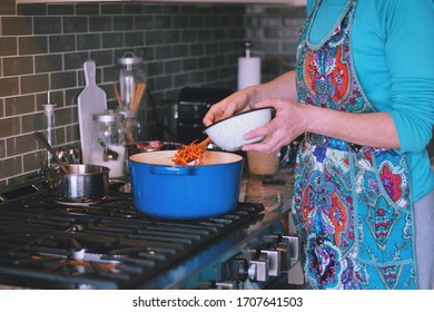 Woman Is Cooking Dinner In A Blue Cast Iron Pot, Dutch Oven, On A Stove