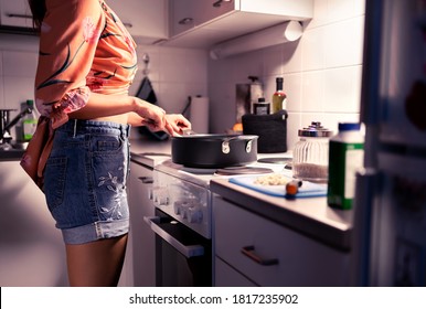 Woman cooking dinner in home kitchen at night. Healthy vegan or vegetarian diet. Stir food in frying pan on stove. Happy person preparing meal. Housewife or student making a dish. Modern lifestyle. - Powered by Shutterstock