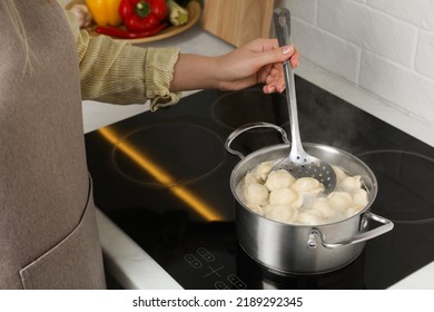 Woman cooking dumplings in saucepan with boiling water on cooktop, closeup - Powered by Shutterstock