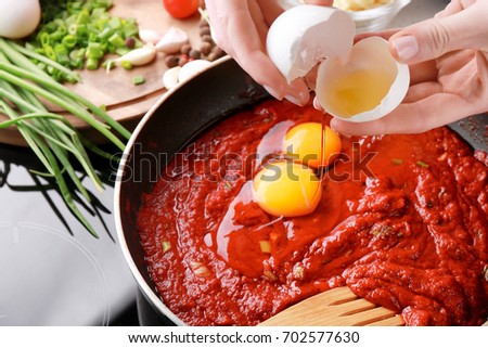 Woman cooking eggs in purgatory on stove