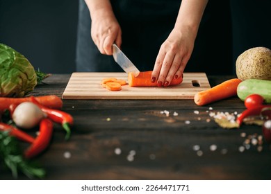 Woman cooking in kitchen at home. Closeup of female hands slicing carrots on chopping board. Culinary, healthy eating concept - Powered by Shutterstock