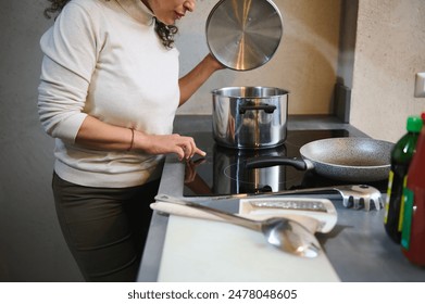 Woman cooking meal in a modern kitchen using an induction stove, showcasing culinary skills and home cooking.