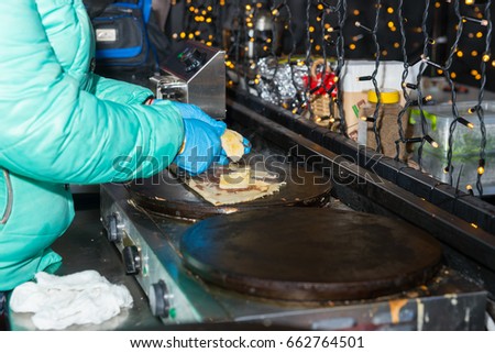 Woman is cooking pancakes with a banana and other topings at outdoor food festival