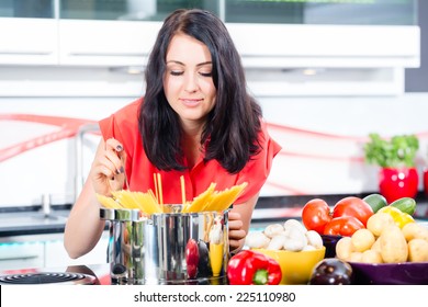 Woman Cooking Pasta In Domestic Kitchen