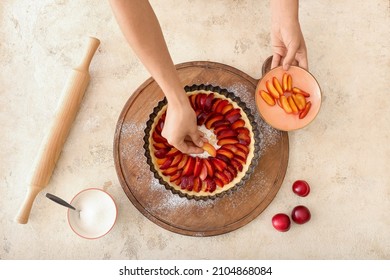 Woman cooking plum pie on light background - Powered by Shutterstock