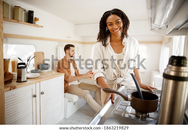 Woman cooking\
in rv kitchen, camping in a\
trailer