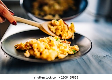 Woman Cooking Scrambled Eggs With Bacon In Frying Pan