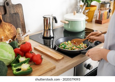 Woman Cooking Tasty Rice With Vegetables On Stove In Kitchen, Closeup