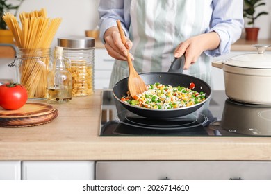Woman cooking tasty rice with vegetables on stove in kitchen, closeup - Shutterstock ID 2026714610