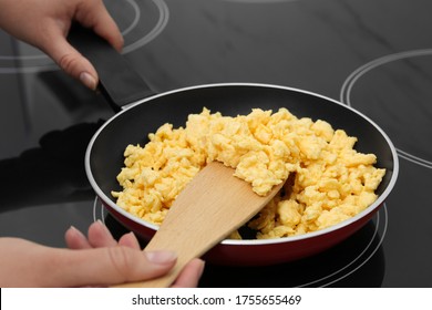 Woman cooking tasty scrambled eggs in frying pan on stove, closeup - Powered by Shutterstock