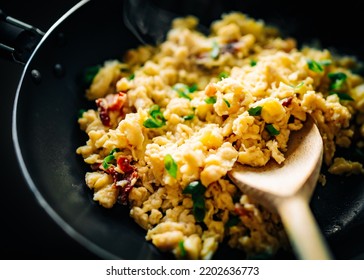 Woman cooking tasty scrambled eggs in frying pan 