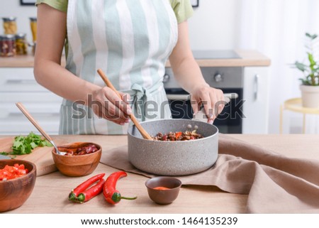 Woman cooking traditional chili con carne in kitchen