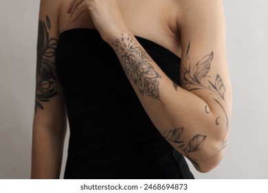 Woman with cool tattoos on light background, closeup