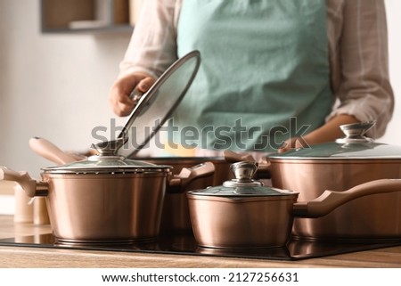 Woman with copper pots cooking in kitchen, closeup