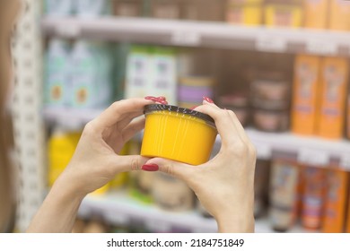 A Woman In A Cosmetics Store Holds A Jar Of Body Scrub In Her Hands. Hair Mask. Against The Background Of The Shop Window. Shopping In A Beauty Salon. Woman Testing Face Cream, Applying Body Lotion.