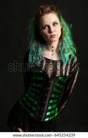 Woman in cosplay corset posing in studio with a green light from behind. Studio photo. Fashion and cosplay