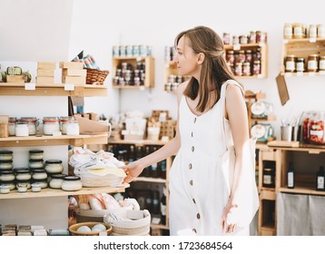 Woman With Cotton Bag Buying Personal Hygiene Items In Zero Waste Shop. Eco Organic Cosmetics. Girl Choose Toiletries Products In Plastic Free Store. Minimalist Lifestyle. Shopping At Local Businesses