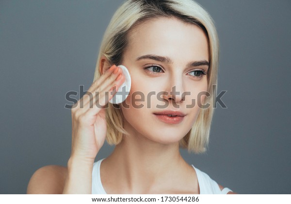 Woman with cotton pad face blonde hair closeup\
female portrait. Studio\
shot.