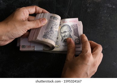 Woman Counting Cash Bundle In Hand Rupees Fifty Denomination Indian Currency Banknotes On Dark Black Background Kerala India. Profit From Business. Top View Monthly Wages, Savings, Money Deposit Bank