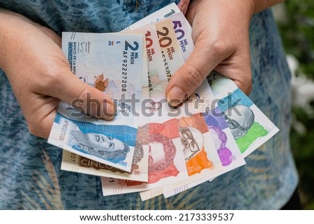 A woman is counting Colombian money, paper bills, all pesos